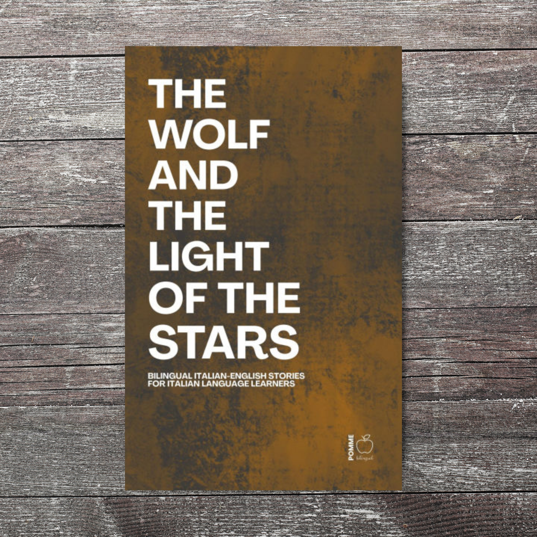 Book cover titled "The Wolf and the Light of the Stars" on a wooden background.